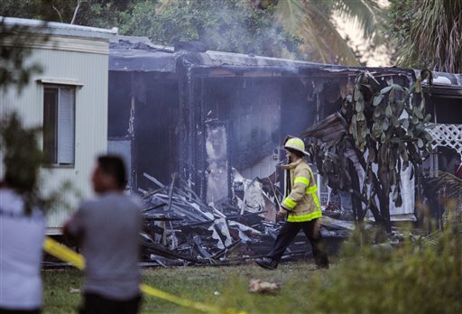 A firefighter walks by a charred mobile home that burned after a small plane crashed in suburban Lake Worth Fla. Tuesday Oct. 13 2015. The aircraft hit several homes at the Mar Mak Colony Club.  MAGS OUT TV OUT