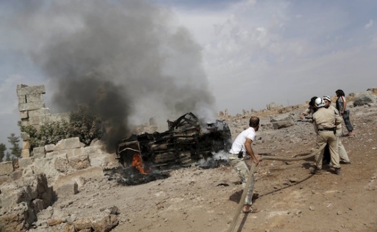 Civil defense members put out the flames on a burning military vehicle in Syria on Oct. 1