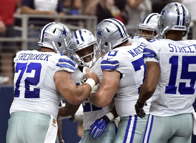 Dallas Cowboys Travis Frederick, Devin Street and others celebrate with running back Joseph Randle second from left smiling after Randle scored his second touchdown in the first quarter on a running play against the Atlanta Falcons in an NFL