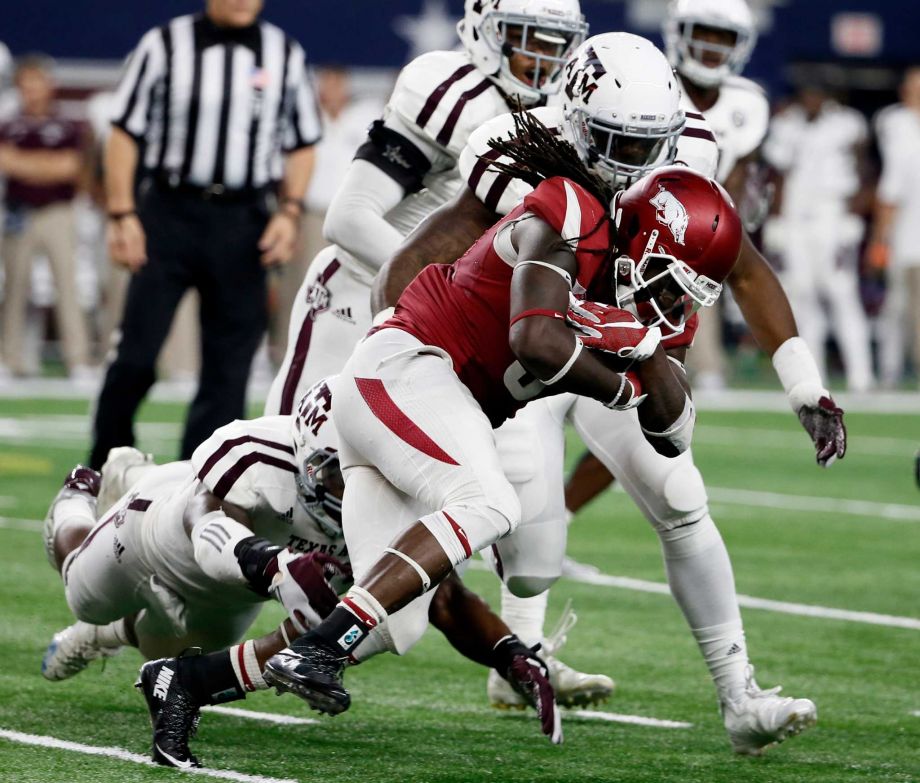 Texas A&M linebackers A.J. Hilliard bottom left and Josh Walker rear combine to tackle Arkansas running back Alex Collins after a short gain during an NCAA college football game Saturday Sept. 26 2015 in Arlington Texas. Collins rushed for 15