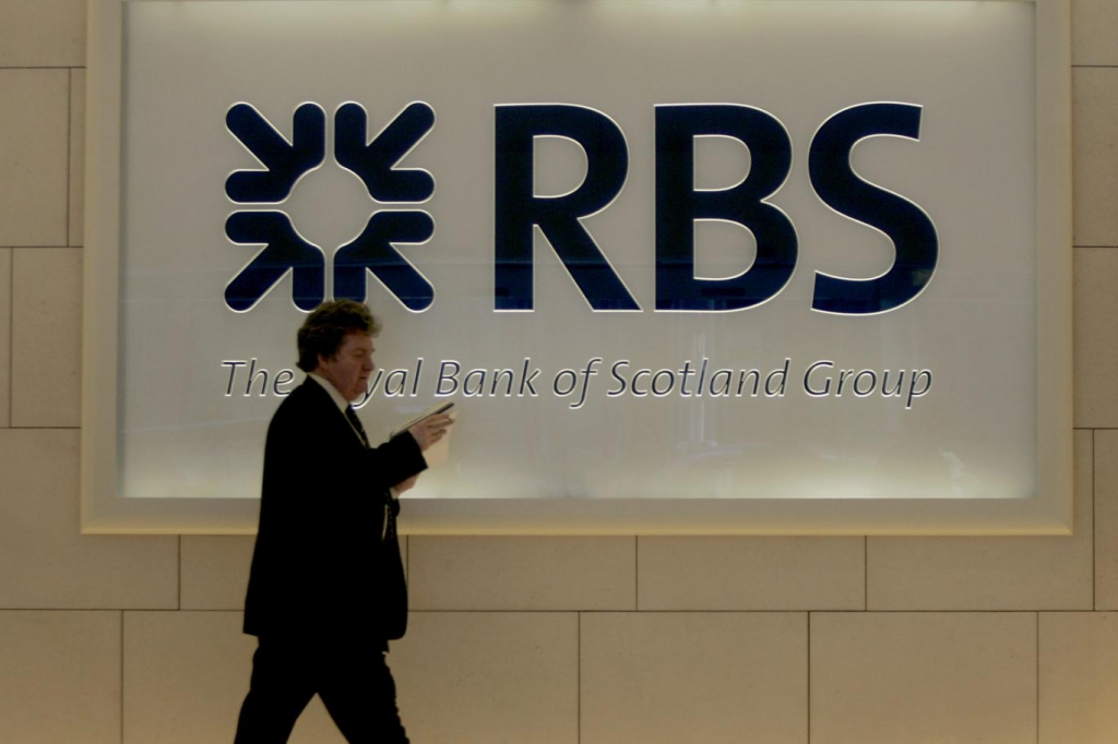 A man walks past a Royal Bank of Scotland logo in the entrance hall of the company's offices in central London