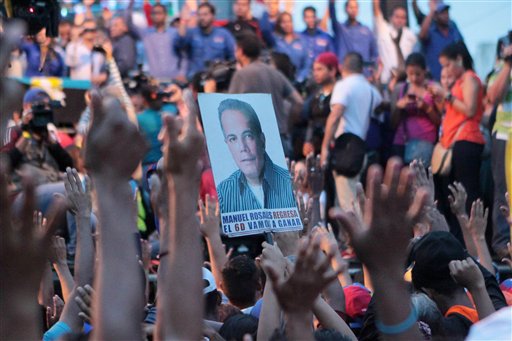 A poster of Venezuelan opposition leader Manuel Rosales is seen in the crowd of supporters waiting for his return in Maracaibo Venezuela Thursday Oct. 15 2015. Rosales a former governor who had been living in exile was arrested when he returned