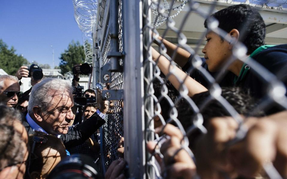 European Migration Commissioner Dimitris Avramopoulos talks to migrant children through a metal fence at the ‘Morias’ camp near the port of Mytilene on the Greek island of Lesvos on Friday