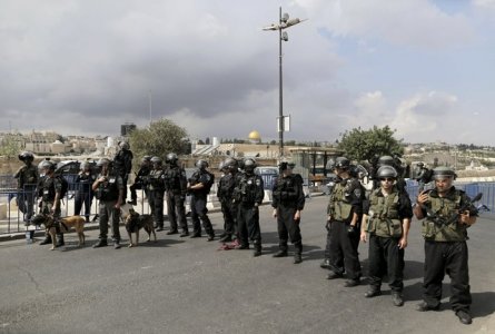 The Dome of the Rock is seen in the background as Israeli policemen stand guard near Palestinian men participating in Friday prayers in Arab east Jerusalem neighbourhood of Ras al Amud