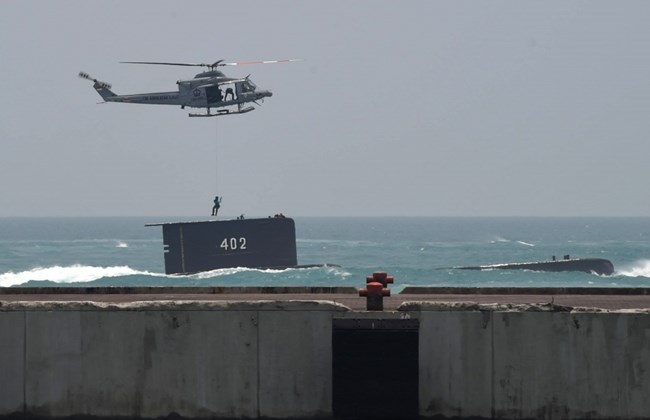 An Indonesian military commando rappels from a helicopter to a submarine during an exercise at a naval base in Cilegon West Java province