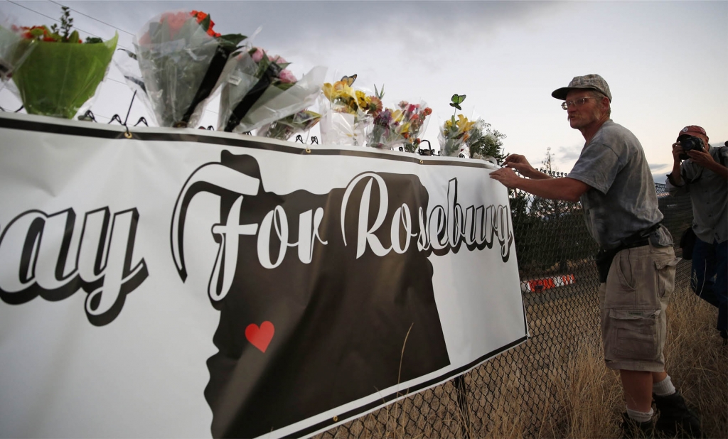 Michael Garwood places flowers at a makeshift memorial near the road that leads to Umpqua Community College Friday Oct. 2 2015 in Roseburg Ore. Armed with multiple weapons Chris Harper-Mercer 26 walked into a classroom at the college Thursday and