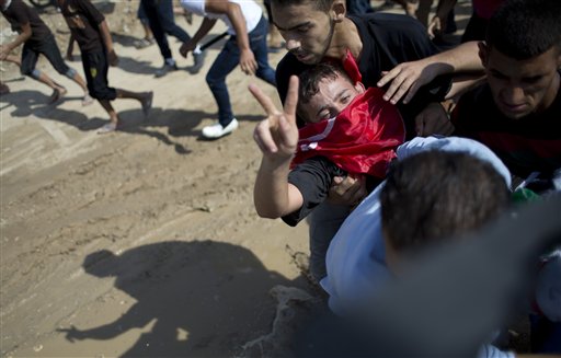 Palestinians carry a wounded man who flashes a victory sign as others run for a cover during clashes with with Israeli soldiers on the Israeli border Eastern Gaza City Friday Oct. 9 2015. At least four attacks  three by Palestinians and one by