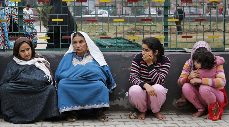 Kashmiri women sit on a footpath after they rushed out of buildings following tremors in Srinagar