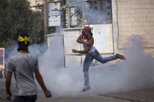 A Palestinian protester throws back a tear gas canister that was fired by Israeli troops during clashes in the West Bank town of al-Ram north of Jerusalem Thursday Oct. 22 2015. Ten Israelis have been killed over the last month mainly in stabbing