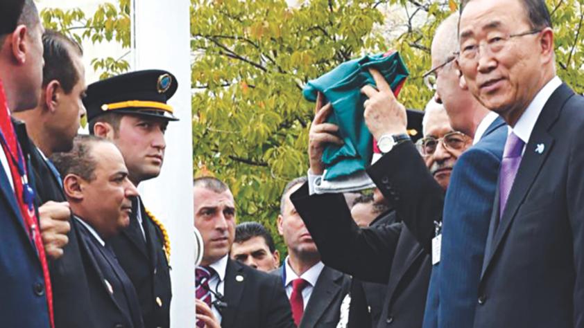 Mahmoud Abbas raises a folded Palestinian flag at the UN headquarters in New York yesterday