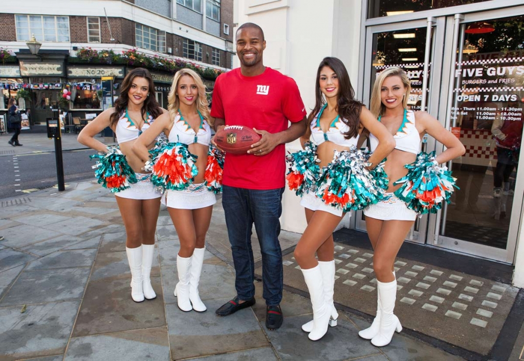 Former NFL star Osi Umenyiora centre and Miami Dolphins Cheerleaders pose for