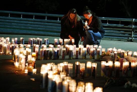 Meriah Calvert left of Roseburg Ore. and an unidentified woman pray by candles spelling out the initials for Umpqua Community College after a candlelight vigil Thursday Oct. 1 2015 in Roseburg Ore