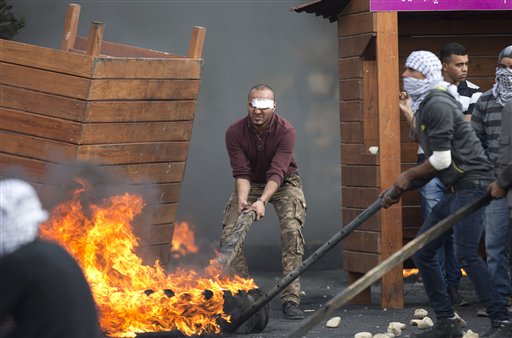 Palestinians push burning tires during clashes with Israeli troops near Ramallah West Bank Friday Oct. 9 2015. Recent days have seen a string of attacks by young Palestinians with no known links to armed groups who have targeted Israeli soldiers and