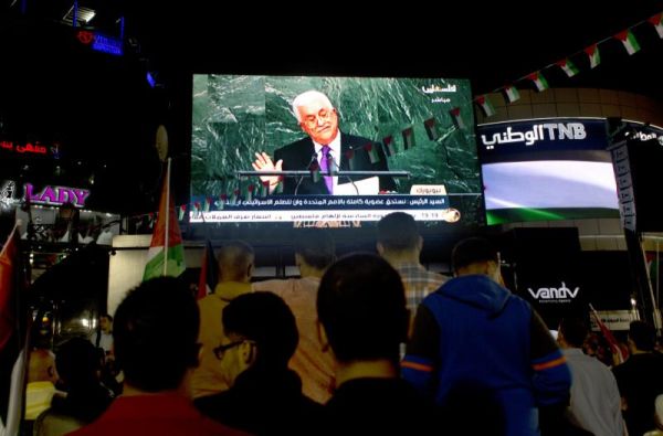 Palestinians watch a speech by Palestinian President Mahmoud