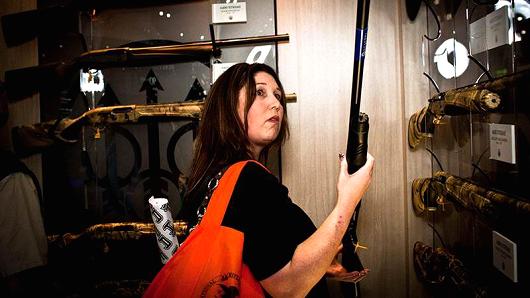 A woman examines rifles at the NRA National Meeting in Houston Texas