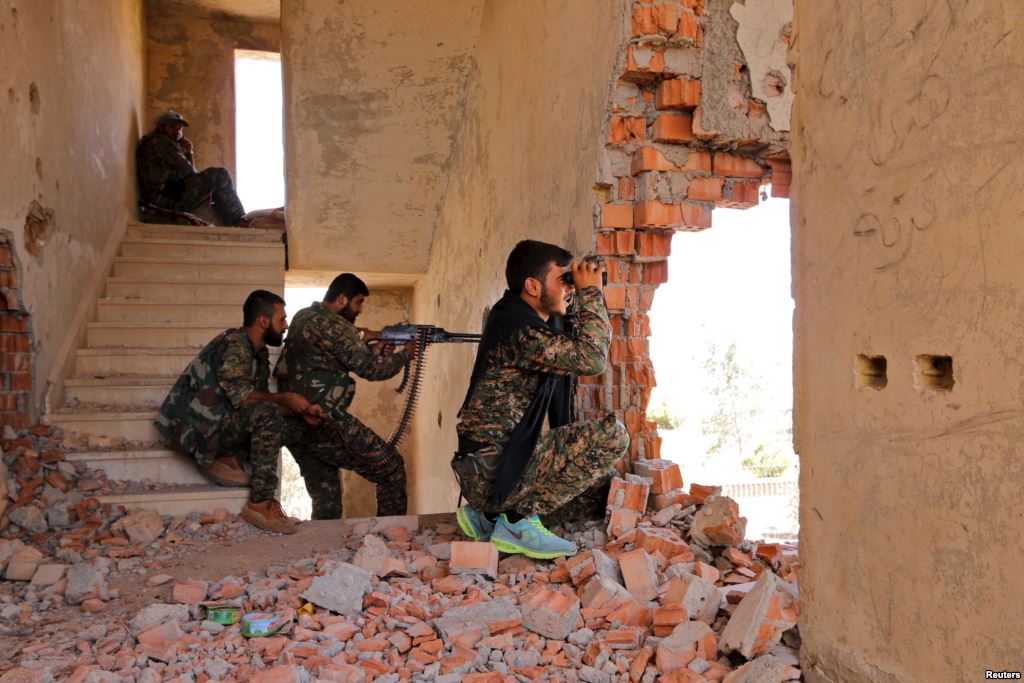 FILE- Kurdish People's Protection Units fighters take up positions inside a damaged building in al Vilat al-Homor neighborhood in Hasaka city as they monitor the movements of Islamic State fighters who are stationed in Ghwayran neighborhood