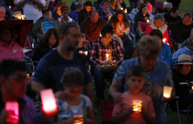 People bow their heads in prayer during a prayer vigil Saturday Oct. 3 2015 in Winston Ore. The vigil was held in honor of the victims of the fatal shooting at Umpqua Community College on Thursday. Charley Thompson left and