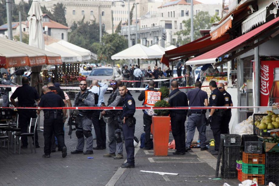 Israeli policemen stand by the body of a Palestinian at the scene of an stabbing attack in Jerusalem Saturday Oct. 10 2015. A Palestinian teenager stabbed two Israelis in Jerusalem Saturday before being shot dead by police forces the latest in a series