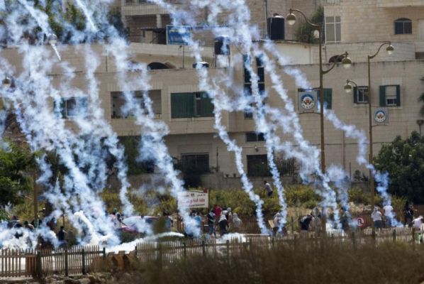 Palestinians run from tear gas fired by Israeli