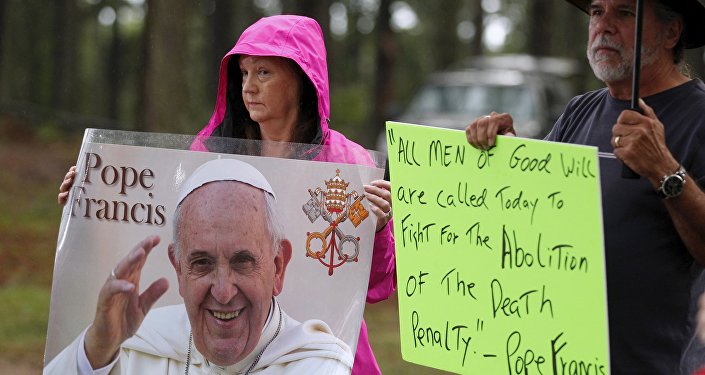 Supporters of Kelly Gissendaner hold signs with an image and quote from Pope Francis as they wait for the execution of Gissendaner at the Georgia Diagnostic and Classification Prison in Jackson Georgia