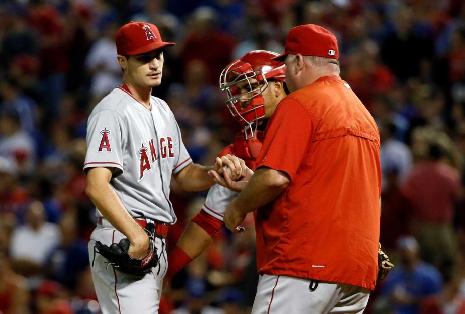 Los Angeles Angels starting pitcher Andrew Heaney turns the ball over to manager Mike Scioscia right as Carlos Perez rear watches in the fifth inning of a baseball game against the Texas Rangers Thursday Oct. 1 2015 in Arlington Texas