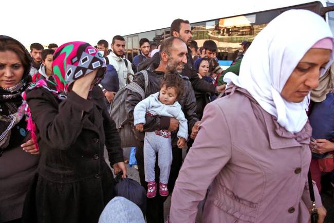 Refugees rushing to get on a bus in Greece