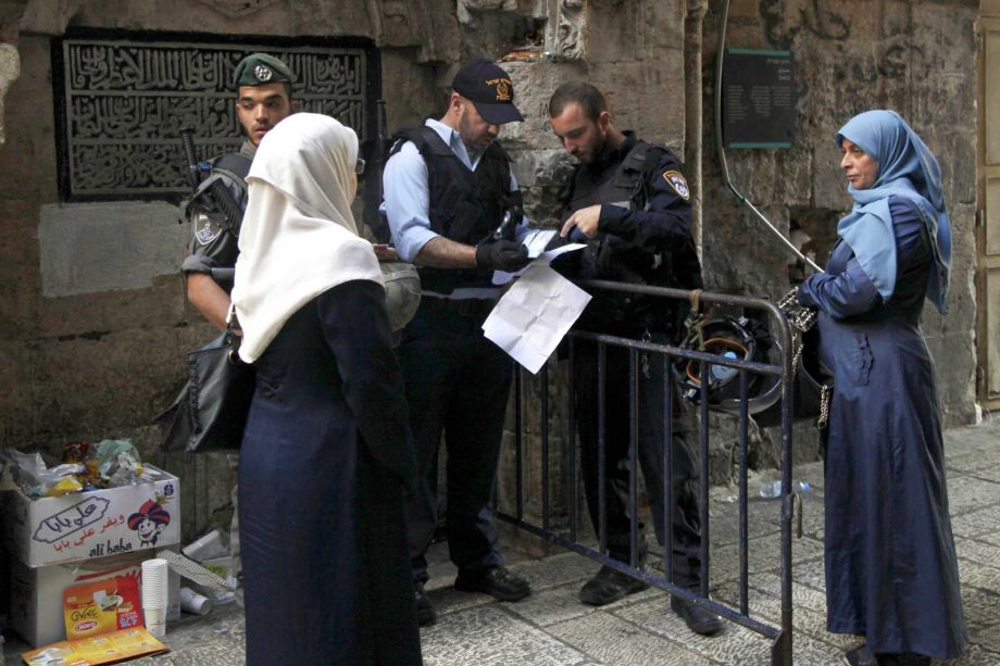 Israeli police check the papers of a Palestinian woman in Jerusalem's Old City Thursday Oct. 8 2015. Israeli Prime Minister Benjamin Netanyahu has barred all Cabinet ministers and lawmakers from visiting a sensitive Jerusalem holy site fearing any hig