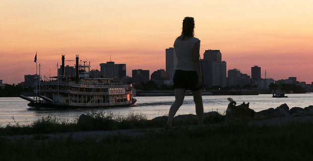 A woman walks atop an earthen levee on the Mississippi River in the Lower 9th Ward as the Steamboat Natchez passes in August 2015 in New Orleans. The city is ringed by hundred of miles of levees to protect against flooding