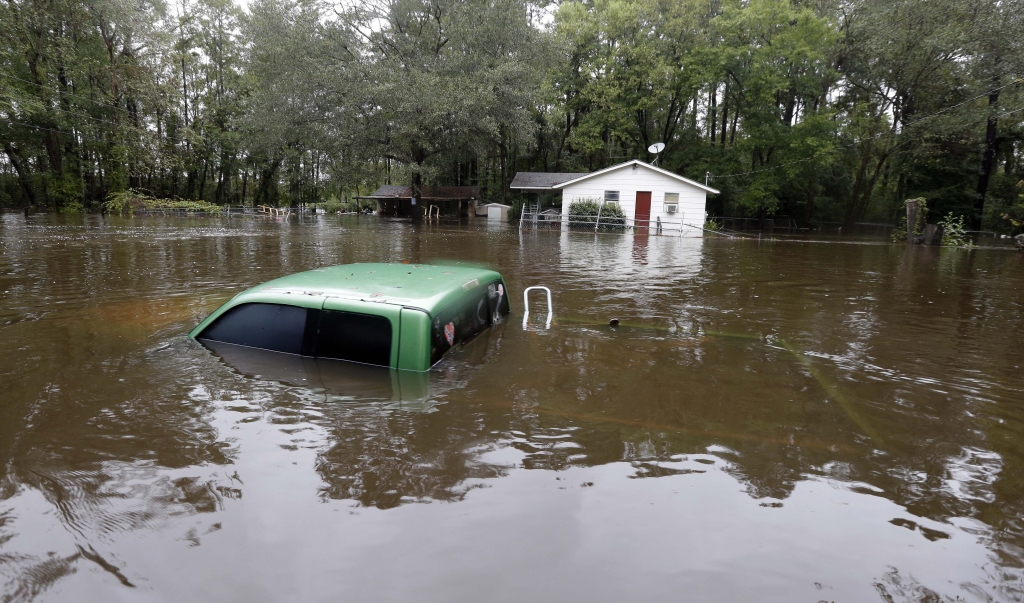 A vehicle and a home are swamped with floodwater from nearby Black Creek in Florence S.C. Monday Oct. 5 2015 as flooding continues throughout the state following several days of rain