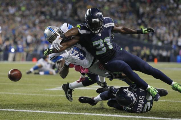 Seahawks&#39 Kam Chancellor makes game-saving play punching the ball out of Calvin Johnson's hands as he is about to score but teammate Seatle K.J. Wright bats the ball out of the end zone illegaly but no flag is thrown