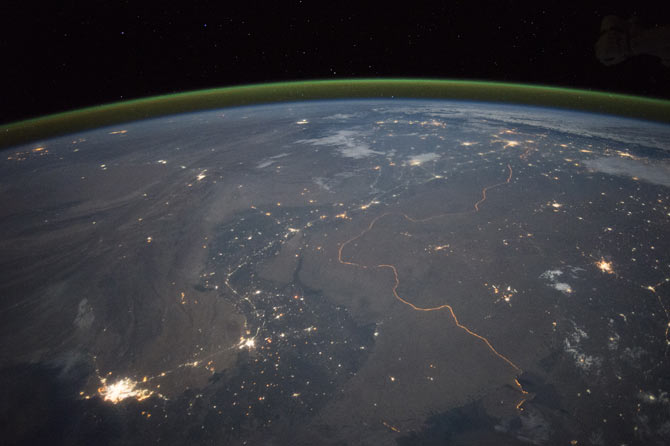 The winding border between Pakistan and India can be seen lit by security lights that have a distinct orange tone