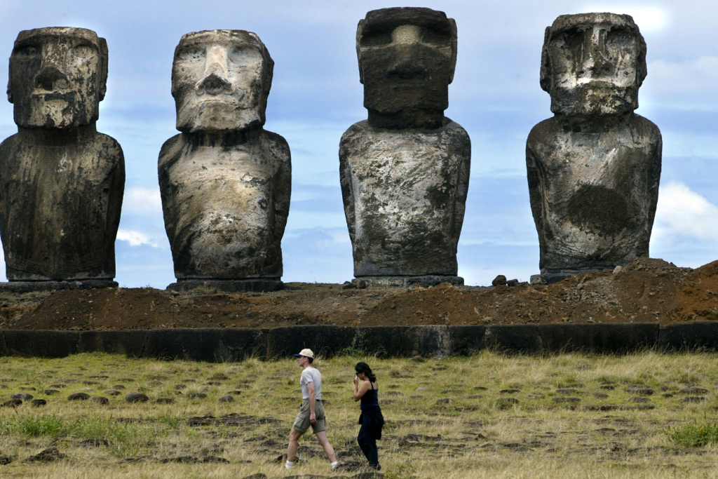 Tourists walk in front of Easter Island’s famous Moai