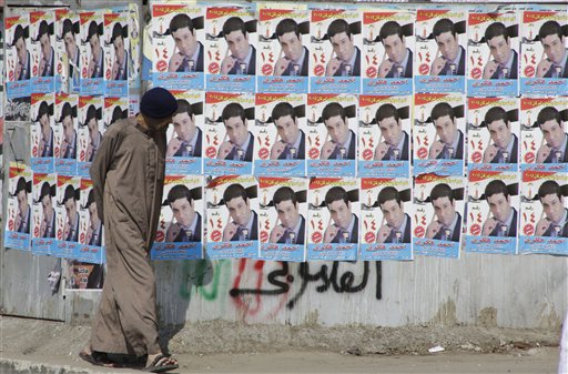 An Egyptian walks in front of posters of a parliamentary candidate in Giza just outside of Cairo Egypt Friday Oct. 16 2015. Egypt's long-awaited parliamentary elections will start on Oct. 18-19 a hoped-for step toward democracy amid a harsh cra