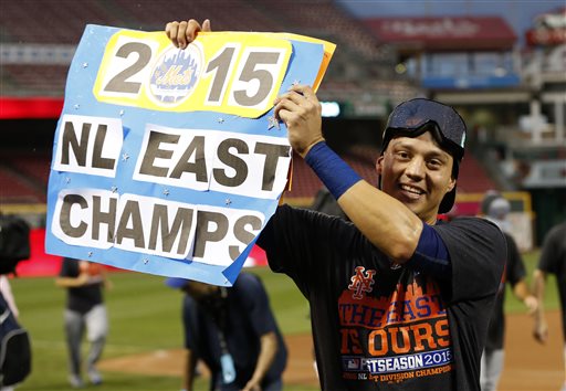 New York Mets&#039 Wilmer Flores holds up a sign as he celebrates after clinching the NL East title following their 10-2 win over the Cincinnati Reds in a baseball game Saturday Sept. 26 2015 in Cincinnati