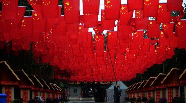 A worker adjusts Chinese national flags following rain at Badachu in Beijing. The Trans Pacific Partnership deal leaves the world's second-largest economy out of the mix