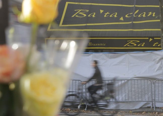 A man rides his bicycle in front of a makeshift memorial next to the Bataclan concert hall in Paris France Wednesday Nov. 18 2015. A woman wearing an explosive suicide vest blew herself up Wednesday as heavily armed police tried to storm a suburban Pa