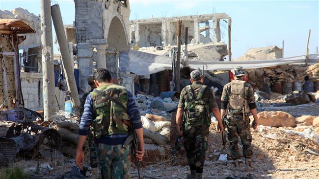 Syrian fighters walk past debris in the town of Arbid on the outskirts of Kweiris military airbase northern province of Aleppo