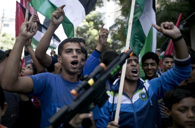 Palestinian youths wave their national flag as they shout slogans during an-anti Israeli protest organized by Hamas and the Islamic Jihad Movement in the town of Khan Yunis in the southern Gaza Strip