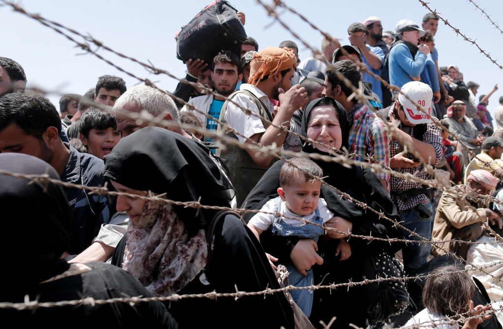 Syrian refugees wait on the Syrian side of the border near Sanliurfa Turkey June 10. Bishop Eusebio Elizondo chairman of the U.S. Conference of Catholic Bishops Committee on Migration says the United States should welcome Syrian refugees and work for