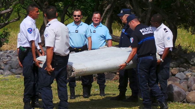 French police officers carry a piece of debris from a plane in Saint-Andre Reunion Island identified as a piece of the missing Flight 370. Australian authorities said Thursday that new analysis confirms they've lik