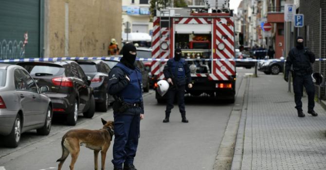 Police officers look on as an operation takes place in the Molenbeek district of Brussels