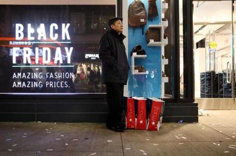 Tom Nguyen stood with his store bags while waiting for his family to return from shopping on Washington Street in Boston on Friday