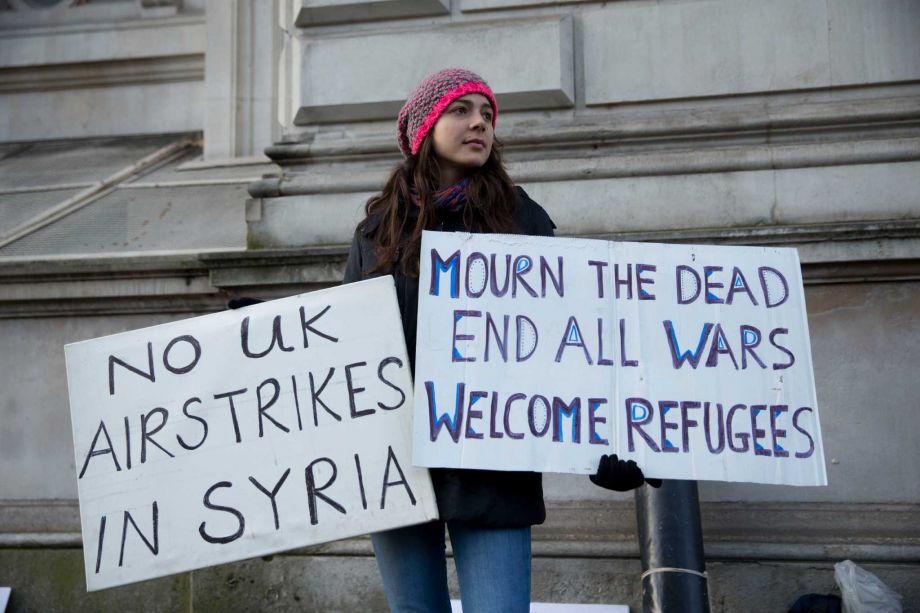 A peace protestor holds placards outside Downing Street London Tuesday Dec. 1 2015. British Prime Minister David Cameron has called for a debate and vote in Parliament on Wednesday on whether Britain should launch airstrikes against militants in Syria