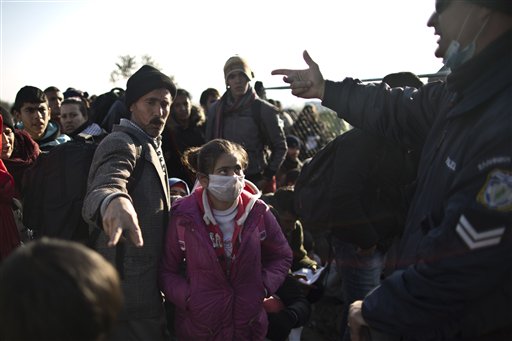 Yazidi refugee Samir Qasu 45 center from Sinjar Iraq and his daughter Dunia 13 gestures to a Greek police officer while he an d his family and other refugees and migrants wait to be permitted to cross the Gree