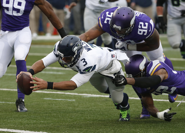 ASSOCIATED PRESS           Seattle Seahawks quarterback Russell Wilson dives for a eight-yard touchdown run as Minnesota Vikings cornerback Antone Exum defensive tackle Tom Johnson try to bring him down in the first hal