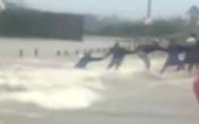 Human chain formed by some men to help a man from drowning