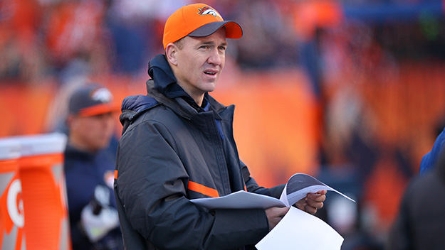 Injured quarterback Peyton Manning of the Denver Broncos looks over game notes on the sideline