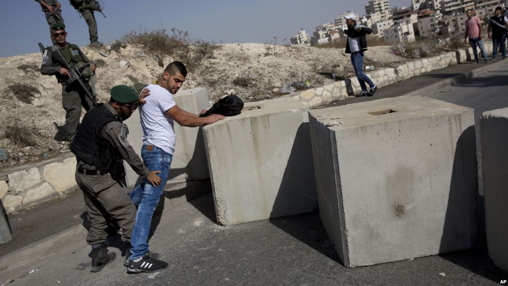 FILE- Israeli border police search a Palestinian next to newly placed concrete blocks in an east Jerusalem neighborhood Oct. 15 2015. Israeli police say they have arrested several young members of a Jewish terrorist group suspected of carrying out a J