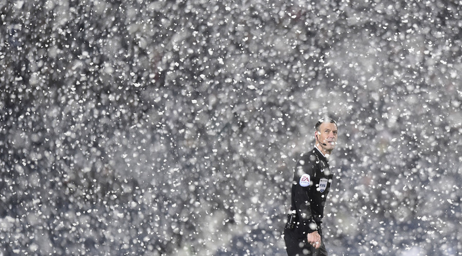 Referee Mark Clattenburg stands in the snow during the English Premier League match between West Bromwich Albion and Manchester City in England