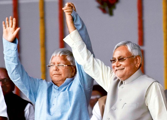 RJD chief Lalu Prasad waves to spectators with Bihar Chief Minister and ally Nitish Kumar after the oathtaking ceremony